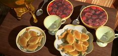 there are many bowls and plates with food on the table next to each other, including raspberries