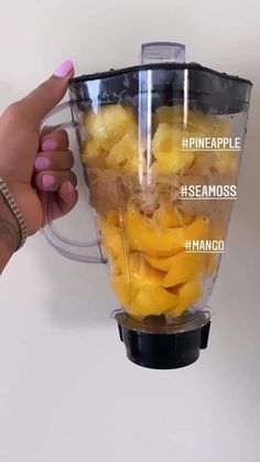 a hand holding a blender filled with mangoes