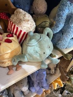 many stuffed animals are sitting on shelves in a toy store, one is holding a cake