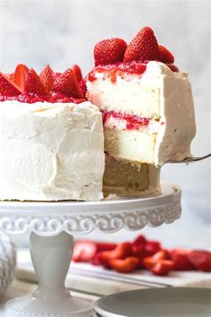 a piece of cake with white frosting and strawberries on top is being held by a fork