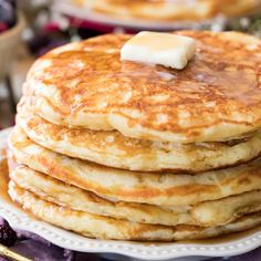 a stack of pancakes with butter on top and blueberries in the background, ready to be eaten