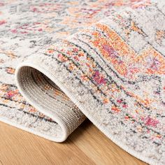 an area rug is laying on top of a wooden floor with a white and orange color scheme