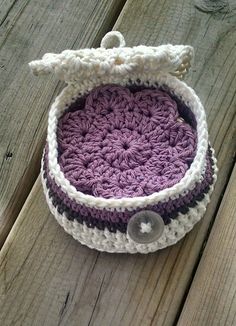 a purple and white crocheted basket sitting on top of a wooden table next to a pair of scissors