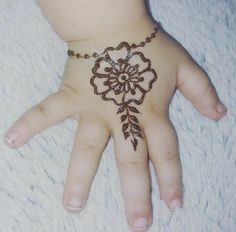 a person's hand with a henna tattoo on top of it and a chain around the wrist