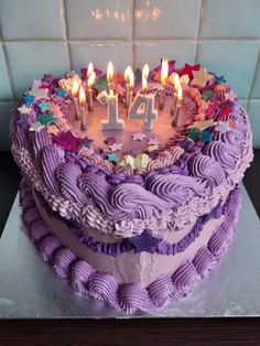 a birthday cake with purple icing and lit candles