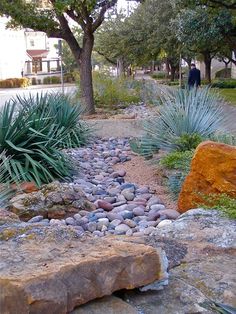 there is a rock and grass bed in the middle of this yard with rocks on both sides