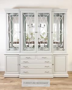 a white china cabinet with glass doors and drawers