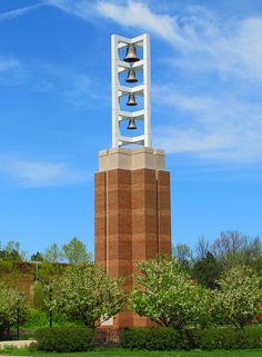 a tall tower with bells on it in the middle of a park and blue sky