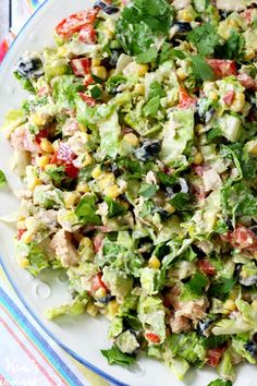 a salad with lettuce, tomatoes, corn and black olives on a plate