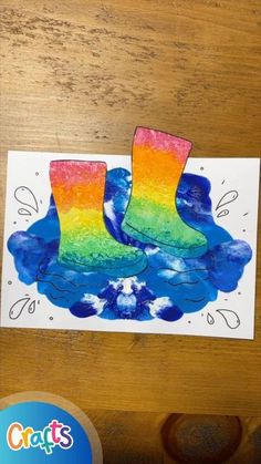 a pair of rainbow boots sitting on top of a wooden table next to a paper cutout