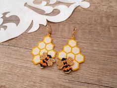 a pair of beaded bee earrings sitting on top of a wooden table