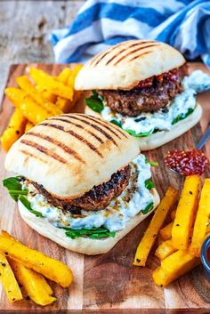 two burgers and french fries on a cutting board