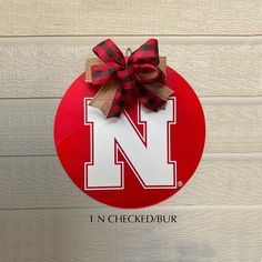 the letter n is tied with a red and black bow on top of a sign