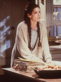 a woman sitting at a kitchen counter with stacks of papers in front of her and looking off to the side