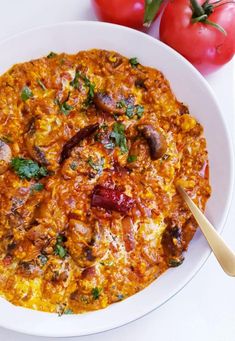 a white bowl filled with food next to tomatoes