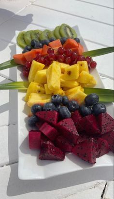 a white plate topped with cut up fruits and veggies next to each other