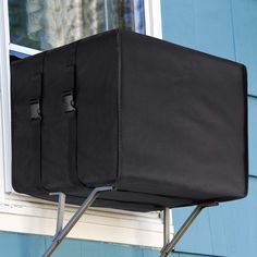 a suitcase sitting on top of a window sill in front of a blue building