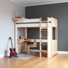 there is a bunk bed with a desk and guitar on the floor next to it