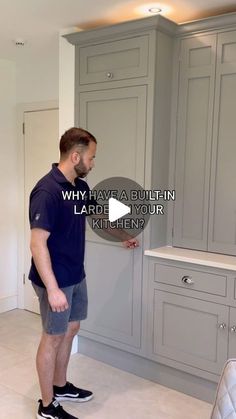 a man is standing in the middle of a kitchen looking at something on the wall