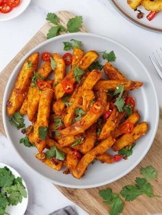 a white plate topped with chicken wings covered in cilantro and red bell peppers