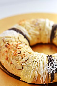 a pastry with white icing and nuts is on a yellow plate, ready to be eaten