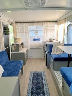 the inside of a camper with blue couches and rugs on the floor