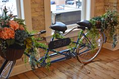 a bicycle is decorated with flowers and greenery in front of a window sill