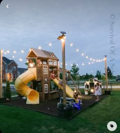 children are playing in the backyard with lights strung over them and a play structure that has a slide