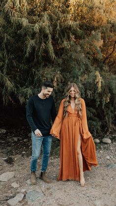 an engaged couple standing in front of some trees