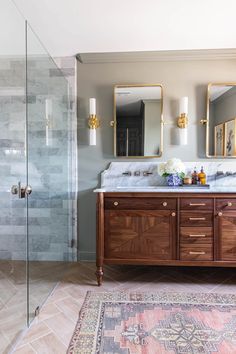 a bathroom with two sinks, mirrors and a rug on the floor in front of it