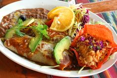 a white plate topped with meat, rice and veggies next to an orange slice