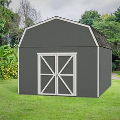 a large gray shed sitting on top of a lush green field