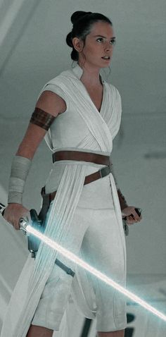 a woman dressed in star wars attire holding a light saber and looking at the camera