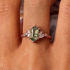 a woman's hand with a ring on it and a green stone in the middle