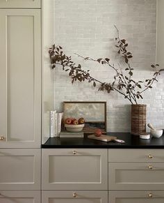 a kitchen with white cabinets and black counter tops is pictured in this image, there are two vases on top of the cabinet