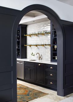 an arched doorway leads into a kitchen with black cabinets