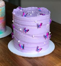 there is a purple cake with butterflies on it and two cakes next to each other