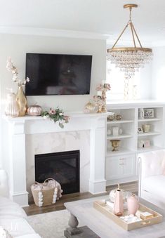 a living room with white furniture and a large tv mounted on the wall above a fireplace