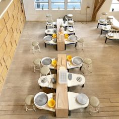 an overhead view of tables and chairs with food on them in a room filled with windows