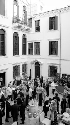 a group of people standing around each other in front of a building with lots of windows