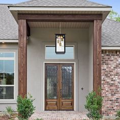 the front entrance to a house with two doors and brick walkway leading up to it