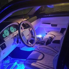 the interior of a car with blue lights and white leather seats is lit up at night