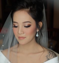 a woman wearing a wedding veil and earrings