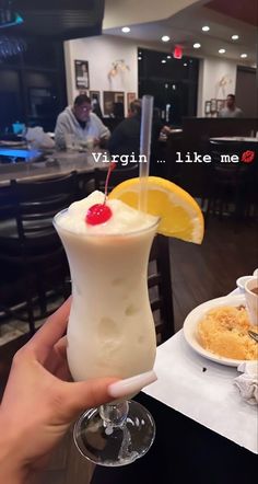 a person holding up a drink with a cherry on top