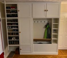 a large white closet with lots of shelves and shoes on top of the cupboards