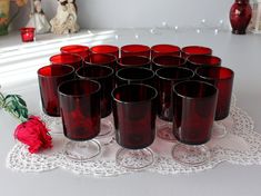 a bunch of wine glasses sitting on top of a doily next to a red rose