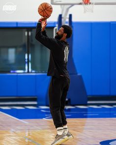 a man is playing basketball in an indoor court with his hands up to the ball