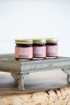 three jars of jam sitting on top of a wooden table