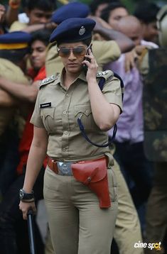 a woman police officer talking on her cell phone in front of a group of people