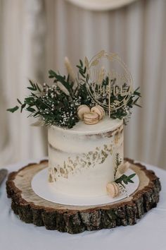 a white wedding cake sitting on top of a wooden slice